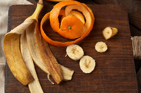棕色木板顶视图上的香蕉和橙色皮图片