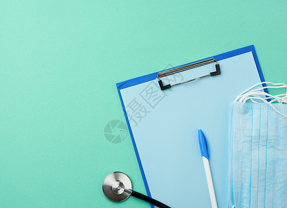 金属听诊器有空白蓝纸绿色背景的一次蓝色医疗面罩顶视平图片