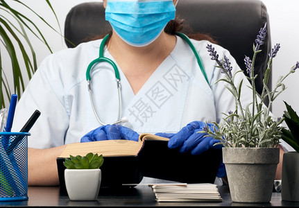 穿蓝制服的医生坐在桌子上看书医生的工作场所背景图片