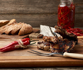 边的烤猪肉牛排躺在厨房切菜板上烤片黑麦面粉包和咸红辣椒图片