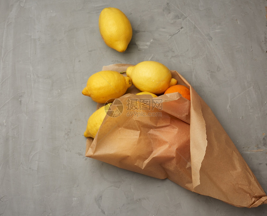 棕色纸袋中成熟的黄柠檬灰色背景顶层图片