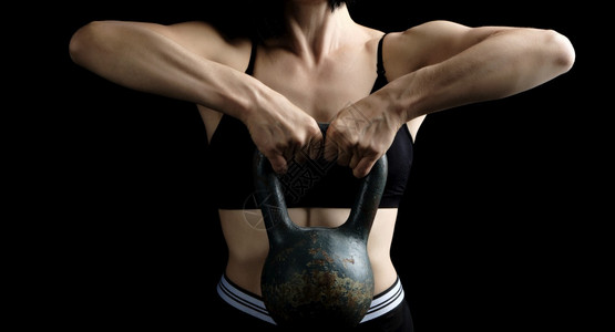 身穿黑顶衣的女子身穿运动材在她面前拿着一个金属叮当肌肉紧张体健壮低键图片