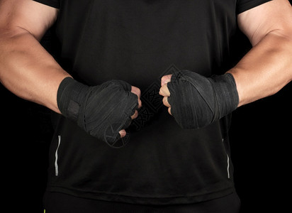 身穿黑色制服的运动员站在一个肌肉紧张的架子上他双手被黑绷带底背包着图片