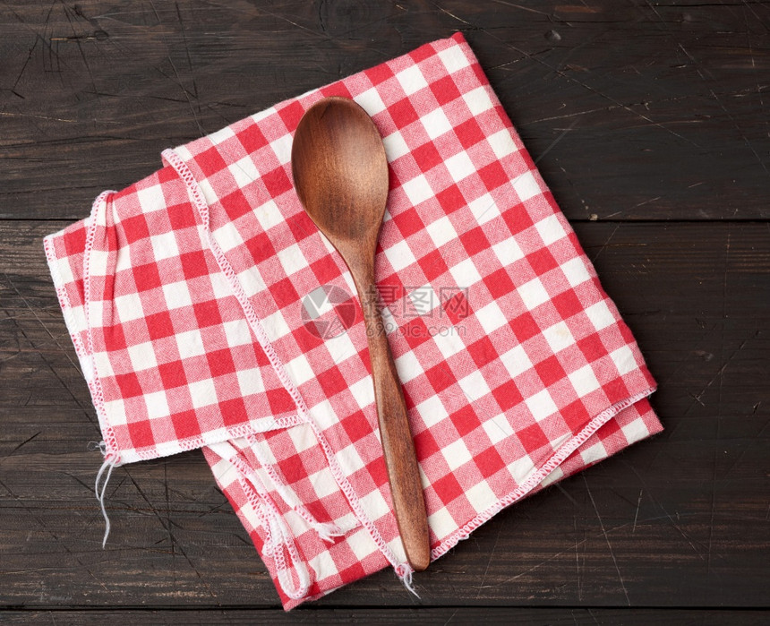 棕色木背景顶视图的木制勺子和红色纺织厨房毛巾图片