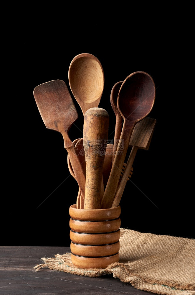各种勺子和厨房木制餐具放在桌上的碗里黑色背景图片
