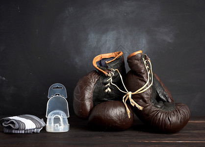 棕色皮革老式拳击手套硅帽和腕绷带木制背景运动设备图片