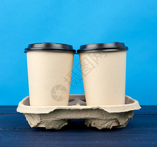 2个棕色纸可支配杯子在木制桌蓝色背景取走集装箱的托盘上用塑料盖子立图片