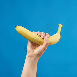 雌手拿着黄熟的香蕉蓝底美味果实图片