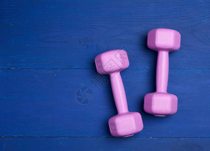 一公斤的粉红色塑料哑铃蓝木背景运动设备图片
