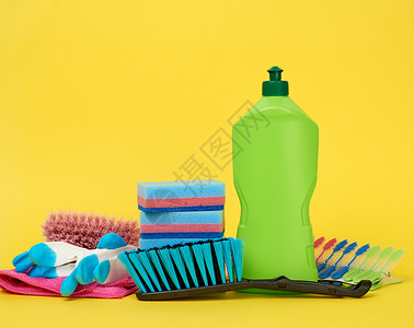 黄色背景绿塑料瓶中清洁多色海绵刷子和清洁液的橡胶手套图片