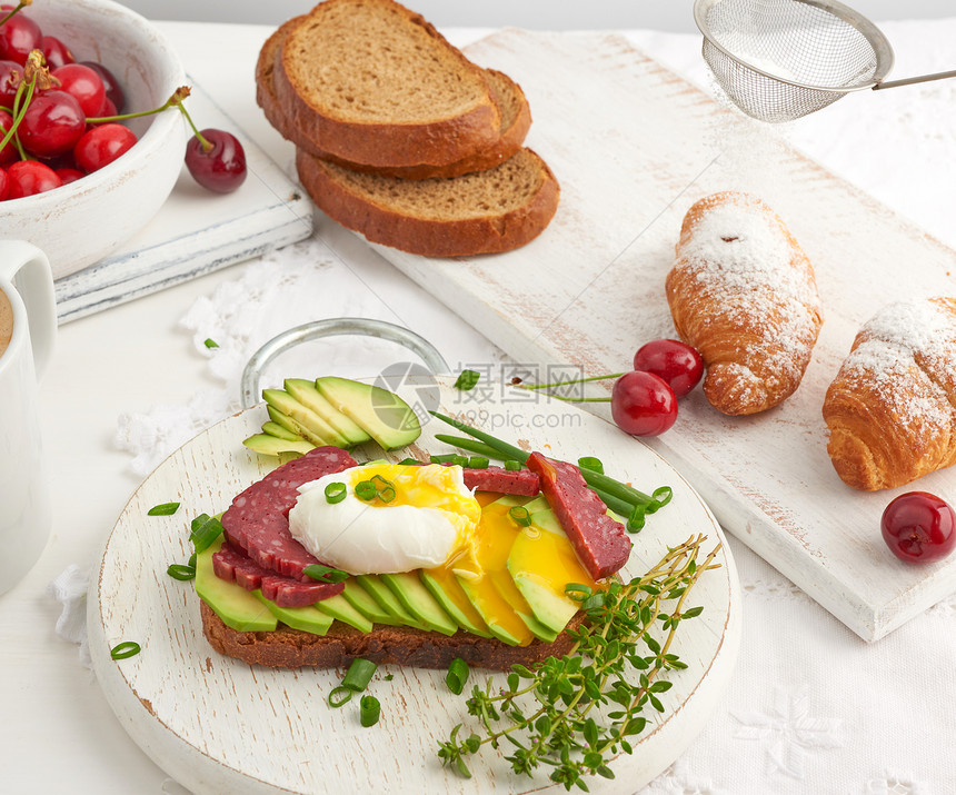 在圆板上羊角面包和成熟红樱桃旁边上午早餐白桌的顶景色图片