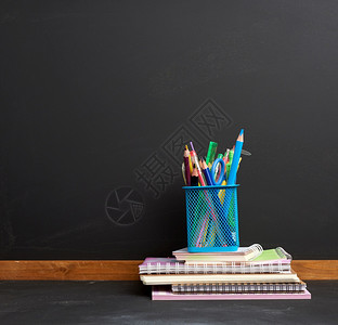 蓝色文具玻璃在空黑粉笔板的背面上带多色木笔的蓝文具玻璃回到学校的概念图片