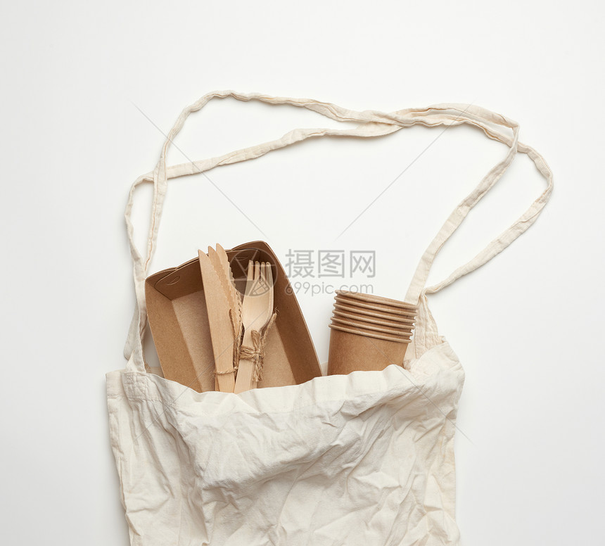 白色背景的棕手工艺纸上的白色纺织品袋和一次餐具图片