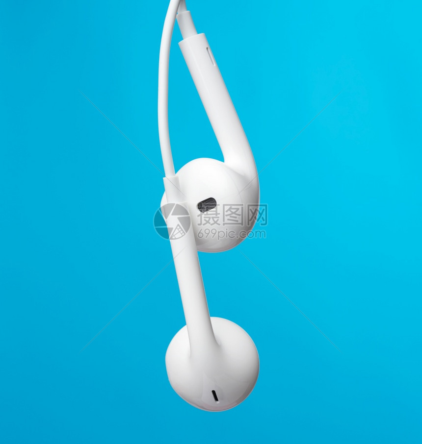 白色电缆上挂着耳机蓝色背景上现代工具关图片
