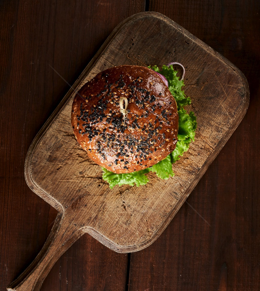 美味的汉堡和芝麻面包在古年棕色切面板上最美的景色木桌图片