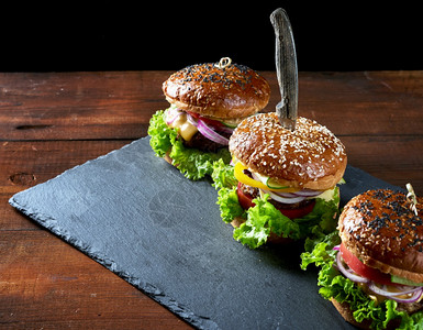 3个美味的汉堡包括炸牛肉切片番茄生菜和洋葱烤白面粉包和芝麻种子图片