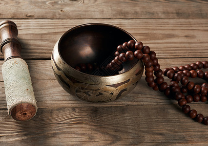 藏歌唱的铜碗在棕色木桌上绑着棍关上图片