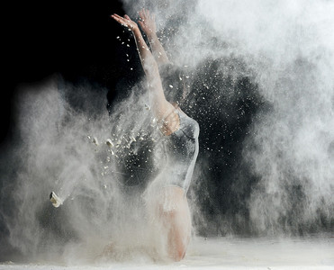 身穿黑色泳装运动服身穿黑色运动服的美女正在黑底面粉的白云中跳舞图片