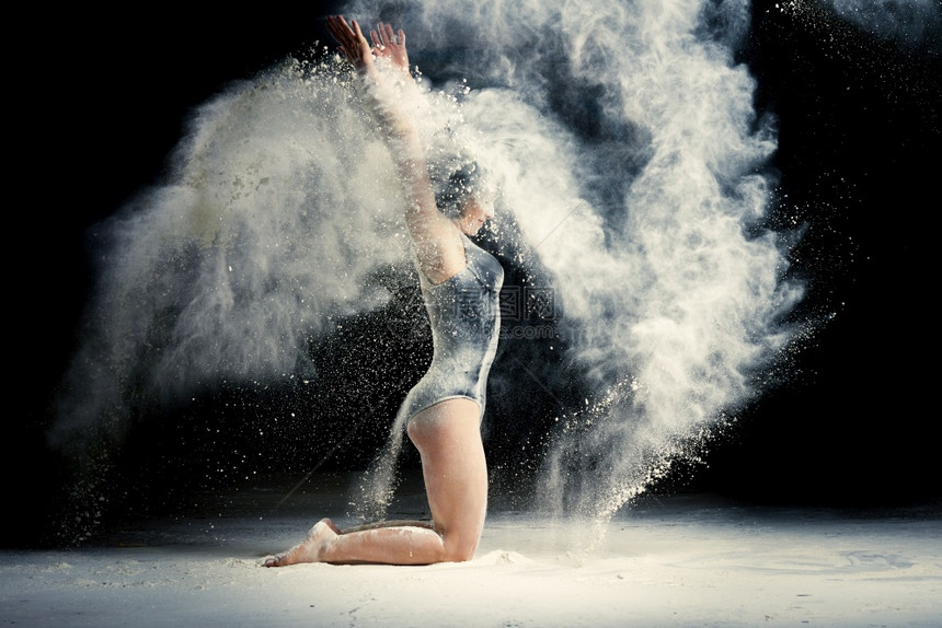 白种女人有运动身体坐在地板上把白面粉扔起来灰尘飞向不同方运动员穿着黑色服图片