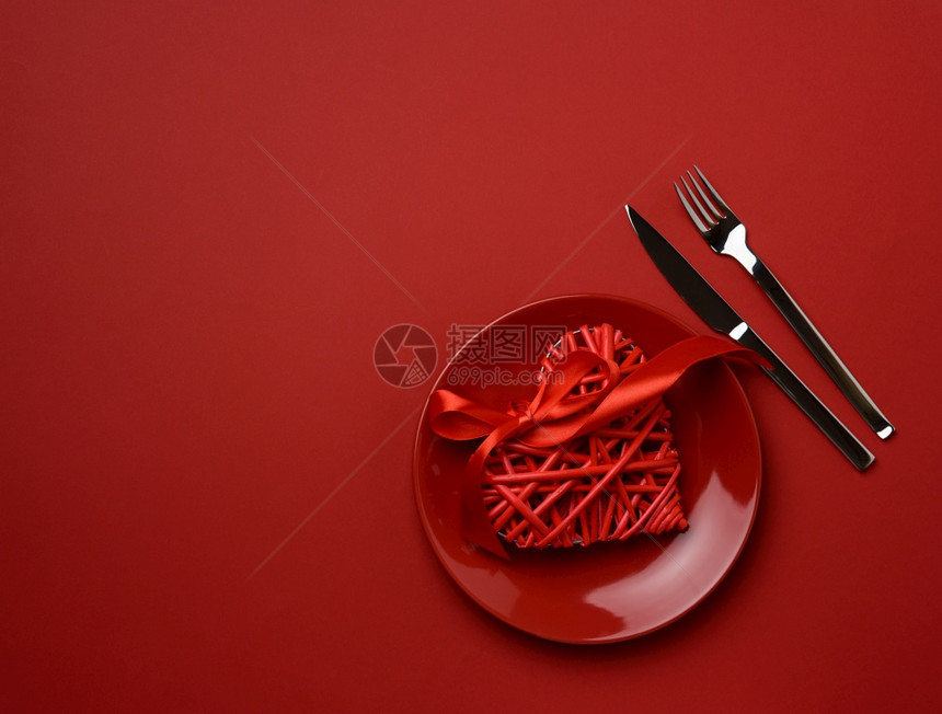 圆陶瓷板和红色背景的刀叉节庆桌布局顶视图图片
