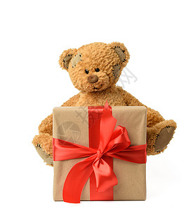 棕色可爱泰迪熊紧靠一个盒子旁边带礼物绑着红色丝带白背景的红丝带图片