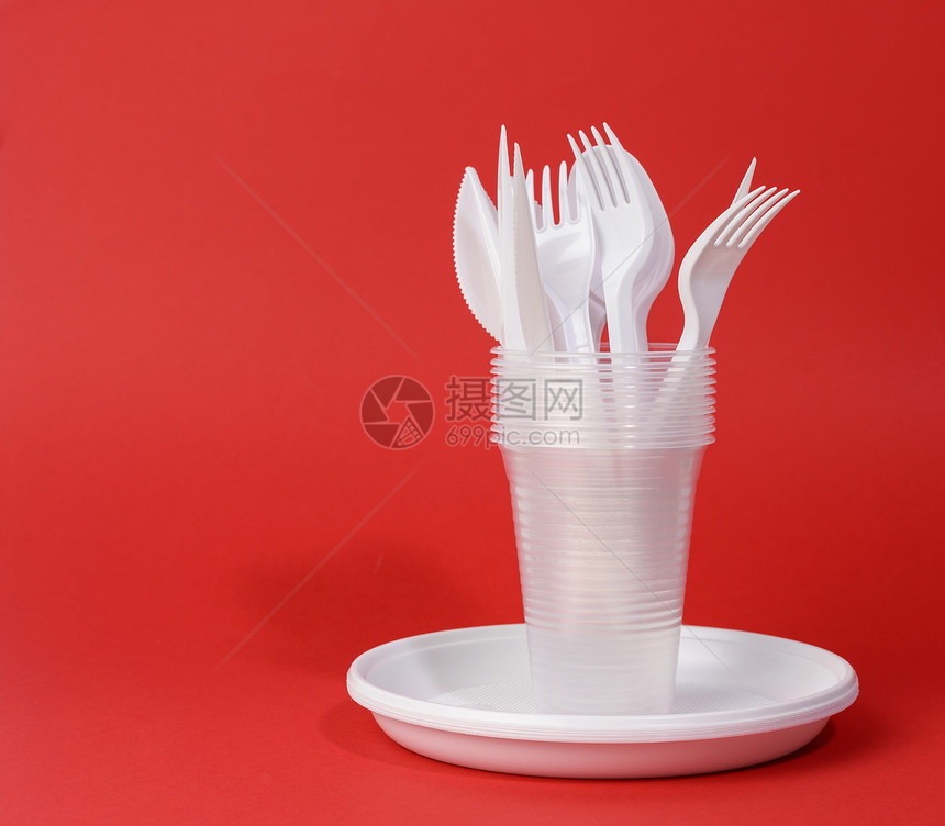 红色背景野餐式白色可支配塑料餐具板杯叉和刀图片