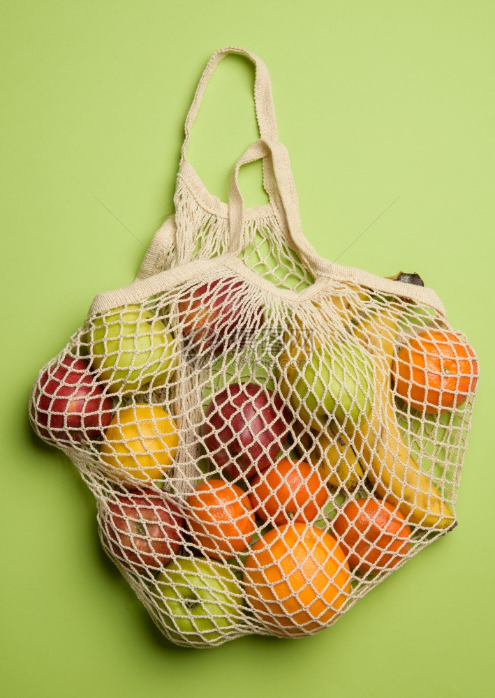 以绿色背景顶视图为的纺织绳袋中成熟新鲜水果图片