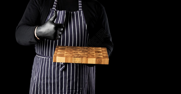 穿条纹蓝色围裙的男厨师手握着空的长方形木制厨房切开板右手像势一样图片