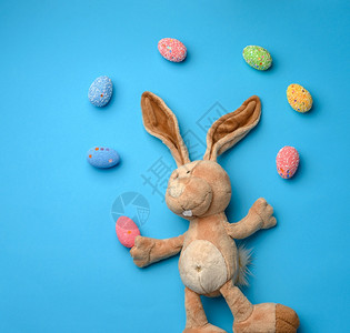 蓝色背景兔子玩偶和带装饰的鸡蛋图片