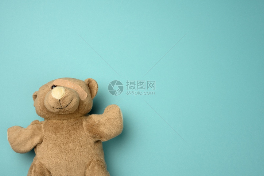 老泰迪熊眼睛上有带护的躺在蓝色背景上顶部视图复制空间图片