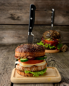 带包肉和蔬菜的芝士汉堡木制背景的肉和蔬菜快餐刀图片