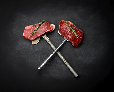 两块生牛肉排躺在铁刀上黑色背景经典牛排顶层风景图片