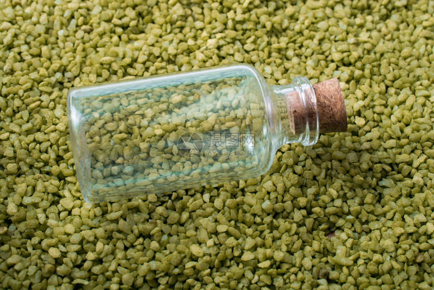 空小瓶子放绿色沙上图片