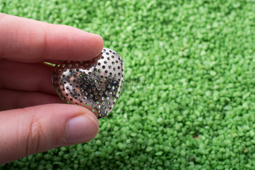 绿色沙地上手握银金属心脏形状图标图片