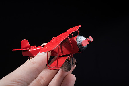 在黑色背景上手持红色玩具飞机背景