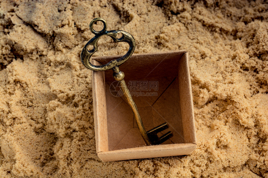 放在沙子上棕色盒中的Retro风格键图片