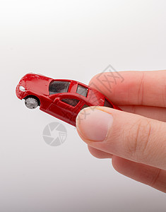 白色背景上手握着多彩的小玩具车背景图片