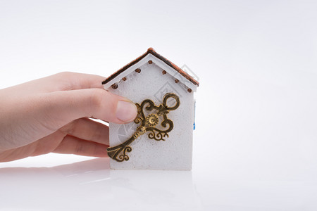 手拿着金钥匙握靠近白色背景的房子背景图片