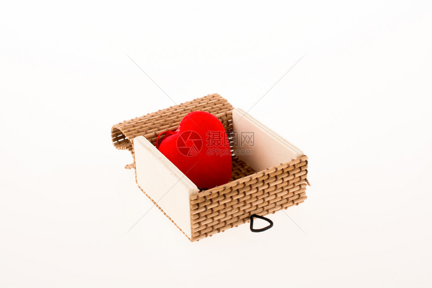 红色心形物体放在白色背景的草盒中图片