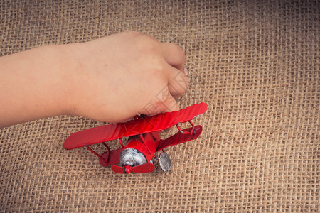 小孩手里的玩具飞机放在麻布上图片