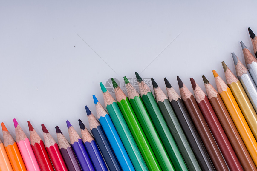 在白背景上放置各种颜色的彩纸笔图片