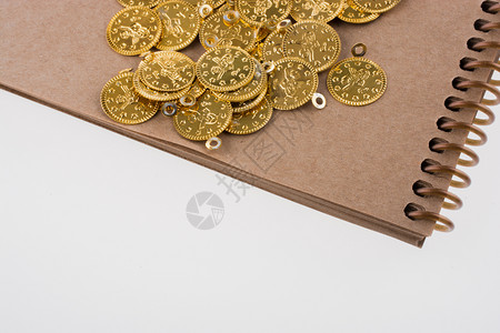 螺旋笔记本和白色背景的金币背景图片