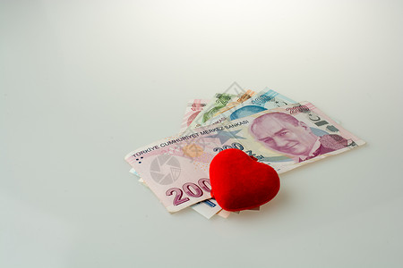 白色背景红心形物体旁的土耳其里拉纸币高清图片