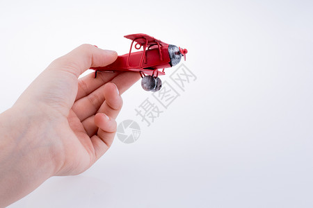 手持白色背景的红色玩具飞机高清图片