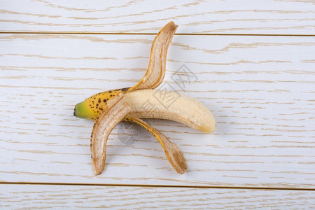 在木制纹身上剥皮的单黄斑香蕉图片