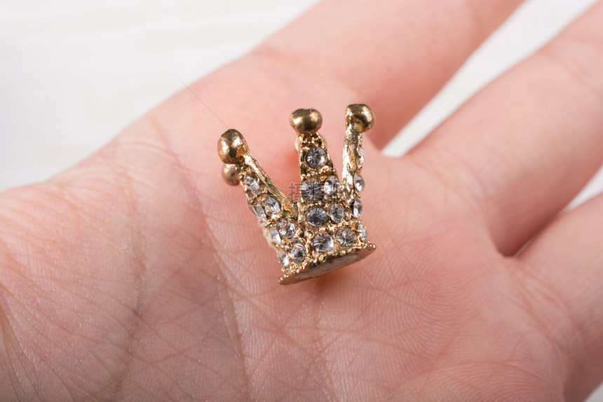 很小的模范王冠被放在手边图片