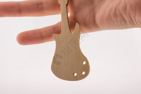 手头白色背景的小型木吉他模图片