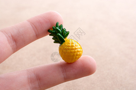 手持一个微小菠萝型图示放在显的背景上图片