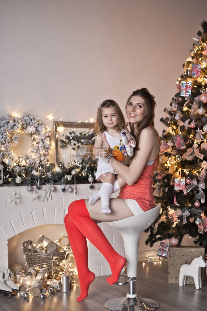 母亲和女儿在壁炉圣诞树周围图片