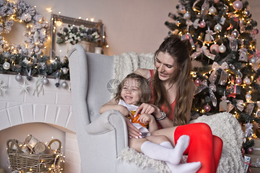 一位美丽的女孩与儿肖像其背景是闪亮的圣诞园地母亲和女儿的背景是闪亮圣诞园地图片
